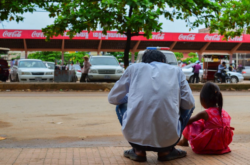 This picture originates from one of our unintentional bus changes in Cambodia: just like us, father and daughter sit on the pavement, waiting for the time to pass and the bus to come.